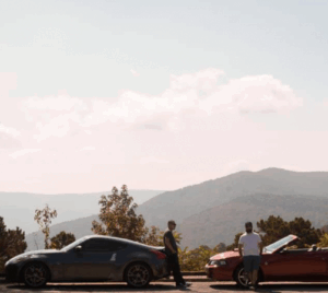 Two men next to their cars, standing in front of the Ouachita Mountain Range on the Talimena Scenic Byway